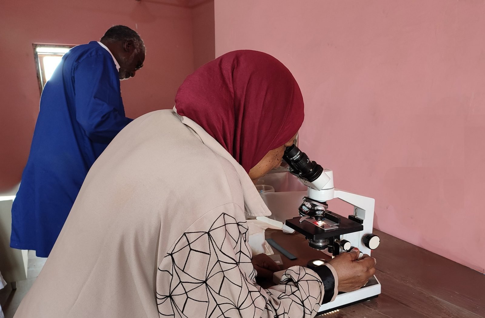 Both professors examining a slide under a microscope.